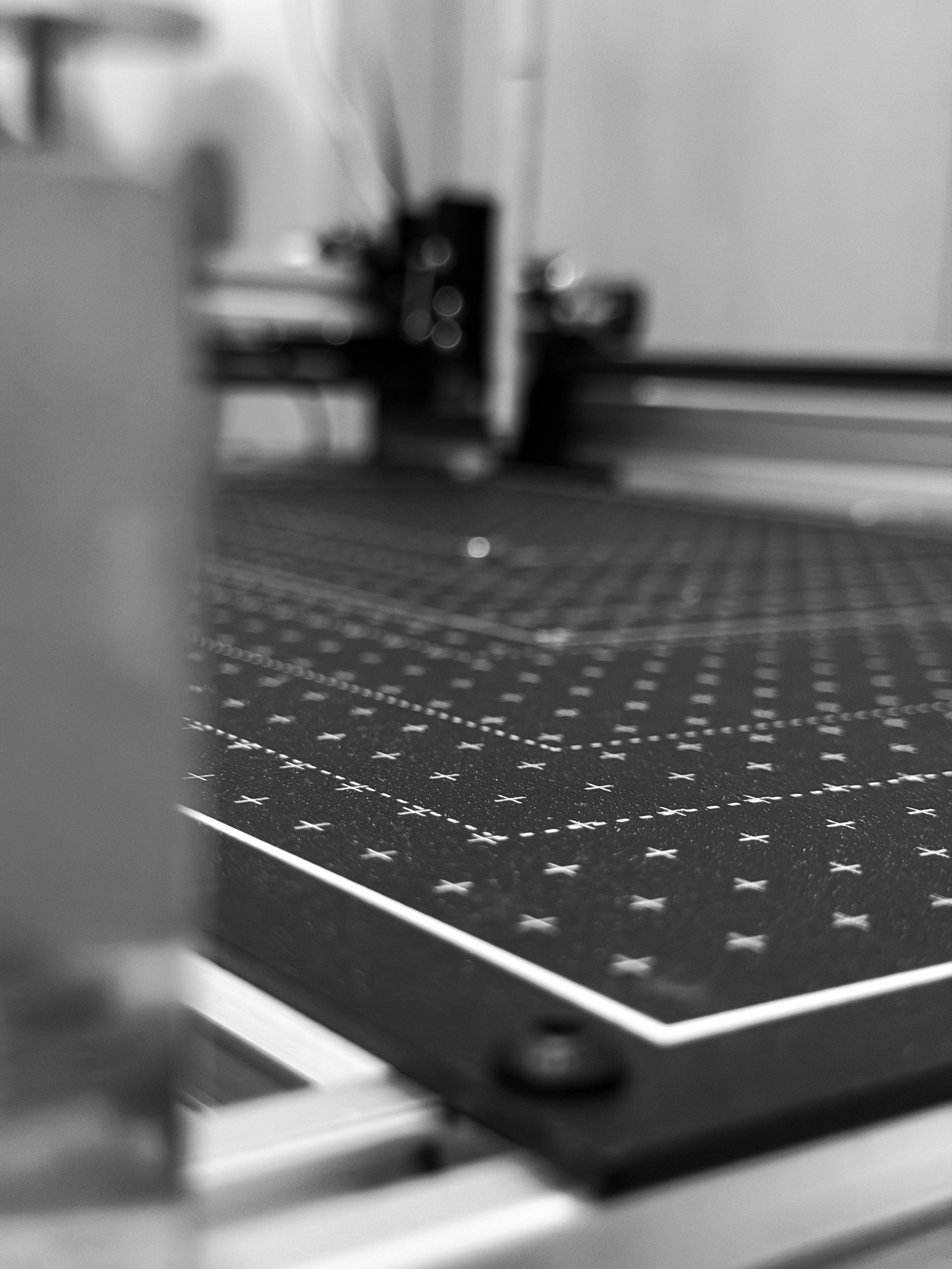 Pen plotter bed mid-run — crosshair registration grid, gantry behind